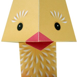 May include: A yellow paper chick with a red beak and feet. The chick has white eyes and a white pattern on its body.