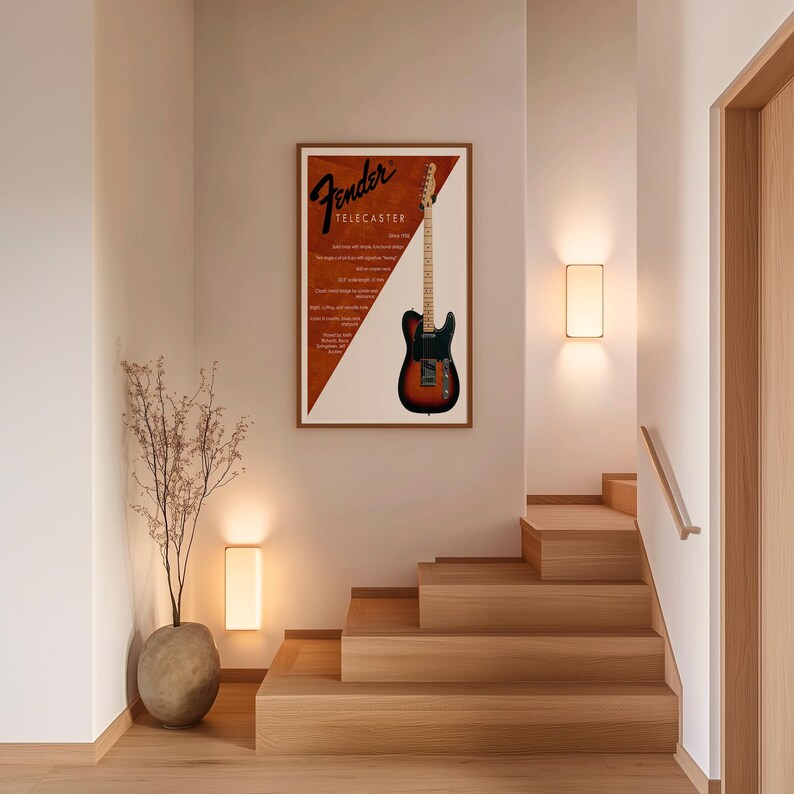 以下が含まれることがあります： Fender Telecasterギターが描かれた額入りのポスター。ポスターは茶色と白の背景にFenderのロゴとギターの詳細が描かれています。ギターは黒、茶色、オレンジ色です。ポスターは木製の階段の近くの壁に掛けられています。
