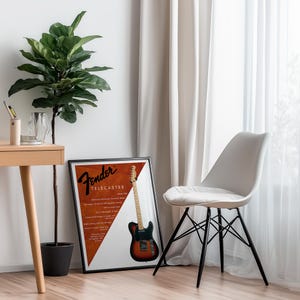 以下が含まれることがあります： 黒いフレームに入ったFender Telecasterギターのポスター。ポスターには、Fenderのロゴとテキストが入った茶色と黒のギターが描かれています。黒い脚の白い椅子がポスターの隣にあります。