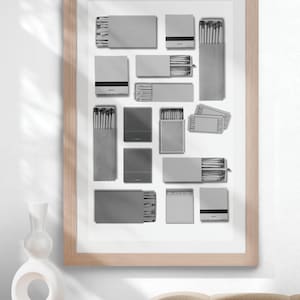 May include: A framed black and white print of various matchboxes arranged in a grid pattern. The matchboxes are all different sizes and shapes, and some have text on them.