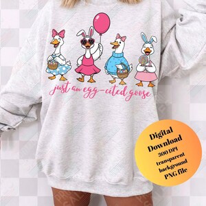 May include: A light gray sweatshirt featuring four cartoon geese dressed for Easter. The geese wear dresses, bunny ears, and hold baskets, a balloon, and a lollipop. The text "just an egg-cited goose" is written across the front.