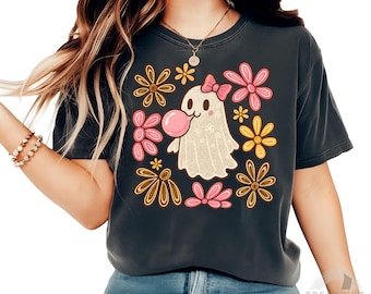 Può includere: T-shirt grigio scuro con un fantasma dei cartoni animati che soffia una bolla di gomma da masticare, circondato da fiori rosa, gialli e marroni. Il fantasma ha un fiocco rosa. Il testo "Digital download - PNG - 300DPI" è in basso.
