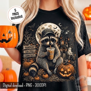 May include: A black t-shirt featuring a graphic of a raccoon wearing a baseball cap and sunglasses, holding a coffee cup. The design includes a full moon, a haunted house, pumpkins, and a sign reading PUMPKINS, HAY RIDES, CORN MAZE.