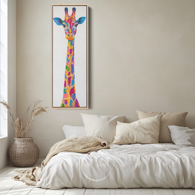 May include: A vibrant giraffe painting in a light wooden frame. The giraffe's long neck and body are adorned with colourful patches of blue, pink, yellow, and orange. The artwork is set against a white backdrop, suitable for a bedroom.
