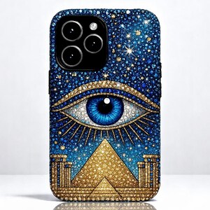 May include: A blue and gold iPhone case with a large, blue eye and a pyramid design. The case is covered in rhinestones.