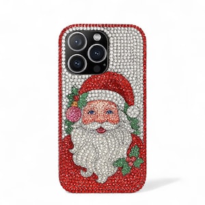 May include: A bedazzled phone case featuring a Santa Claus design. The case is covered in sparkling crystals, with a red border and a Santa Claus illustration in the center. Santa has a red hat, white beard, and blue eyes. The case is designed for a smartphone.