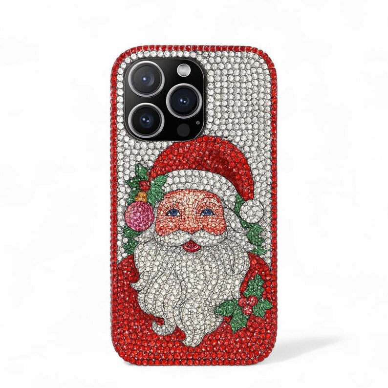 May include: A bedazzled phone case featuring a Santa Claus design. The case is covered in sparkling crystals, with a red border and a Santa Claus illustration in the center. Santa has a red hat, white beard, and blue eyes. The case is designed for a smartphone.