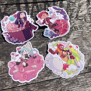 May include: Four colourful stickers featuring cartoon characters. One sticker shows a character sitting on a cupcake, another with a character swinging a weapon, and two others with characters on clouds. The stickers have a white border.
