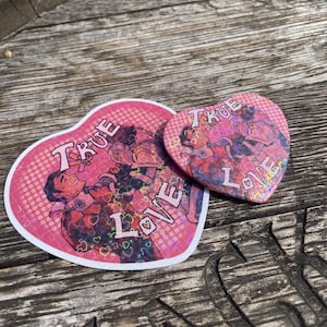 May include: Two pink heart-shaped stickers with holographic glitter. The stickers feature a cartoon couple with the text "True Love" on each sticker.