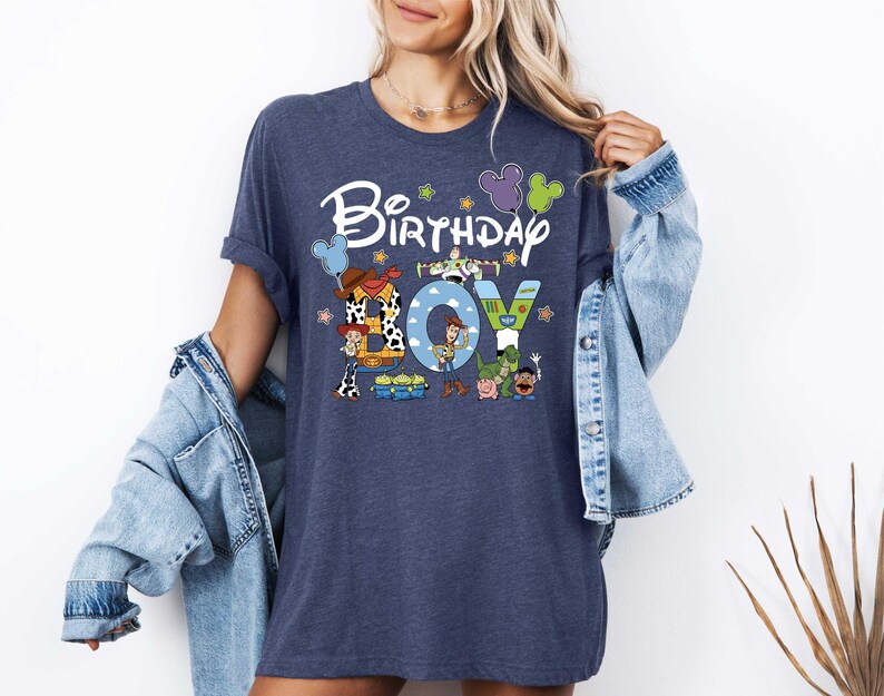 A woman wearing a blue t-shirt with a cartoon character design and the text "Birthday Joy" printed on it.