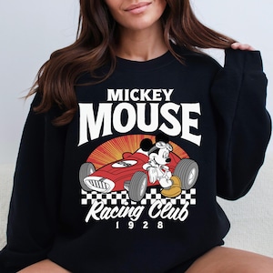 a woman wearing a mickey mouse racing club sweatshirt