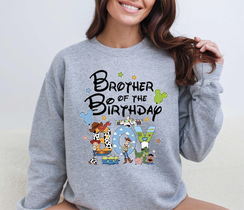 A woman wearing a gray sweatshirt with a cartoon character design and text that says "Brother of the Birthday".