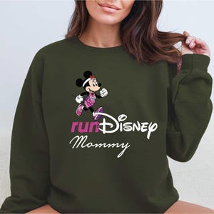 A woman wearing a green sweatshirt with a cartoon character and text printed on it.