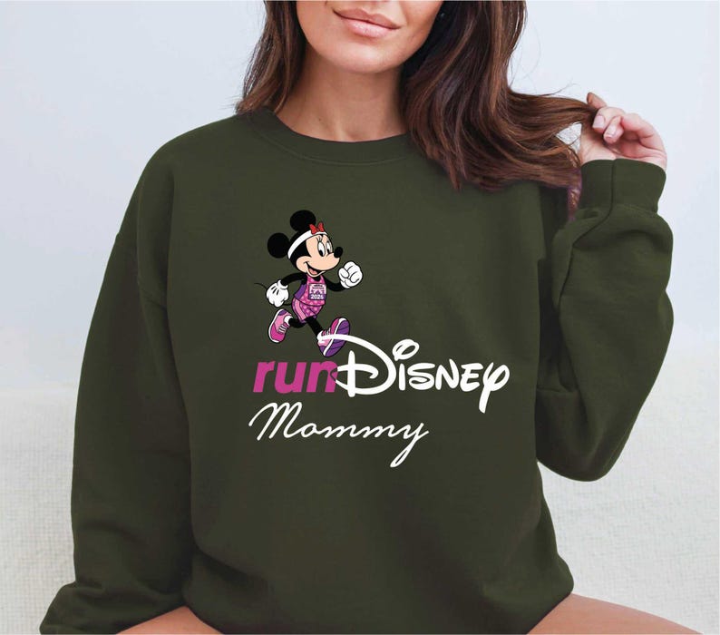 A woman wearing a green sweatshirt with a cartoon character and text printed on it.