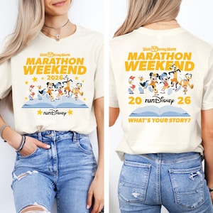 May include: Off-white t-shirt featuring the text "Walt Disney World Marathon Weekend 2026" in yellow. The front design includes Disney characters running on a blue book. The back of the shirt has the same design with the text "What's Your Story?"