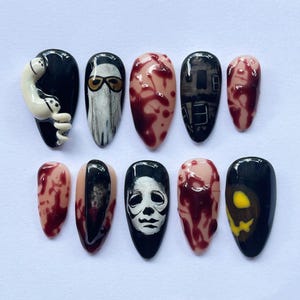 Puede incluir: Un conjunto de diez uñas postizas con temática de Halloween. Los diseños incluyen un fantasma, un fantasma con gafas de sol, salpicaduras de sangre, una casa embrujada y una máscara de Michael Myers. Las uñas son de varios tonos de negro, blanco y rojo.