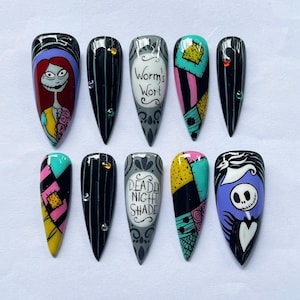May include: A collection of ten long, almond-shaped artificial nails, each with a unique design. Designs include Sally, striped patterns, text reading "Worm's Wort" and "Deadly Night Shade", and patchwork patterns. The nails are painted in bright colours.
