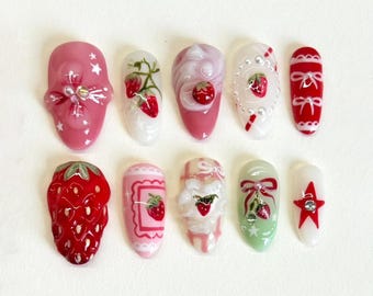 May include: Ten different nail designs featuring strawberries, bows, and stars. The designs are painted on white, pink, and green nail tips.