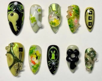 May include: Ten green and black nail art designs featuring various themes, including a key, a rabbit, a flower, and a fish. The designs are painted on a white background.