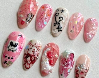 May include: Set of ten pink and white nail tips with various designs, including a cartoon bunny, a floral pattern, and a heart with a star.
