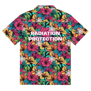 May include: A short-sleeved, button-up shirt with a black background and a colorful floral pattern. The shirt has the text "RADIATION PROTECTION" in white letters with a pink outline.