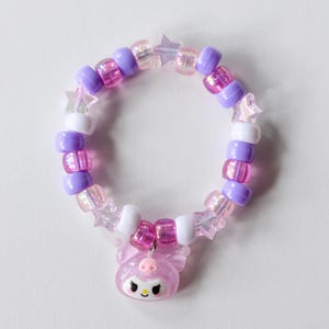 May include: A pink and purple beaded bracelet with a pink star charm. The bracelet is made with small, round beads and features a pink and white star charm.