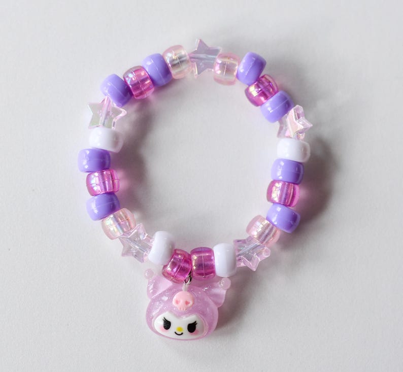 May include: A pink and purple beaded bracelet with a pink star charm. The bracelet is made with small, round beads and features a pink and white star charm.