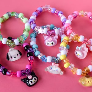 May include: Six colourful beaded bracelets with different character charms. The charms include a dog, a cat, a bunny, a bear, a bird, and a star. The bracelets are made with a variety of beads, including clear, white, pink, blue, green, and yellow.