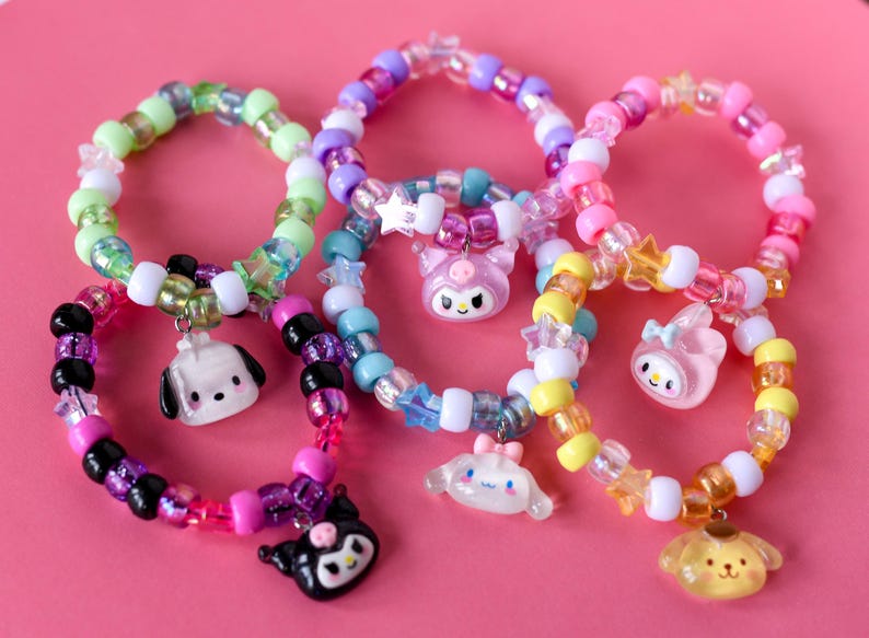 May include: Six colourful beaded bracelets with different character charms. The charms include a dog, a cat, a bunny, a bear, a bird, and a star. The bracelets are made with a variety of beads, including clear, white, pink, blue, green, and yellow.