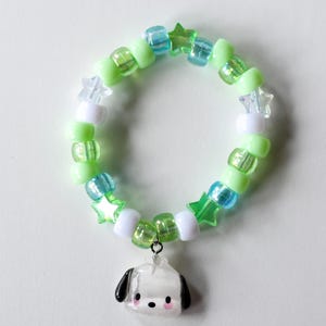 May include: A green and blue beaded bracelet with white star-shaped beads and a white dog charm.