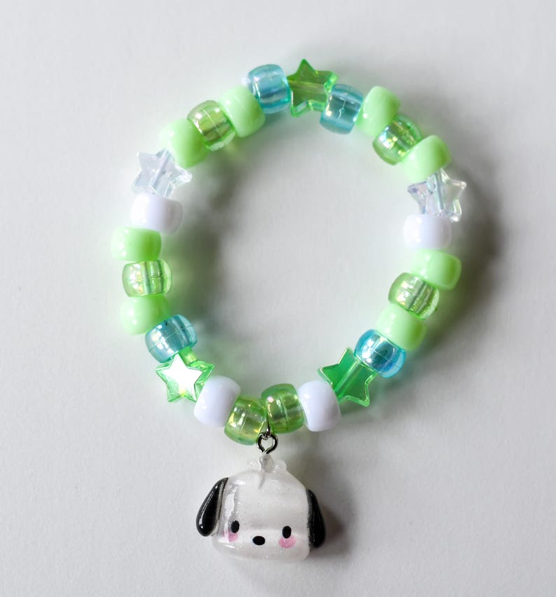 May include: A green and blue beaded bracelet with white star-shaped beads and a white dog charm.