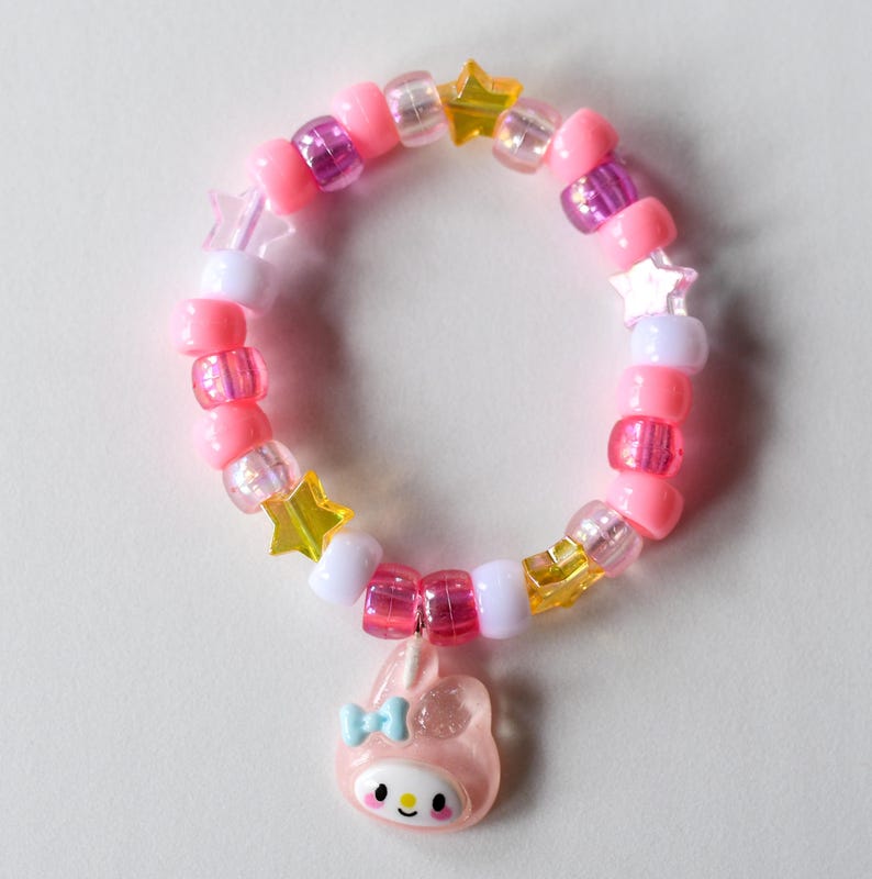 May include: Pink, white and yellow beaded bracelet with a star charm and a pink bunny charm.