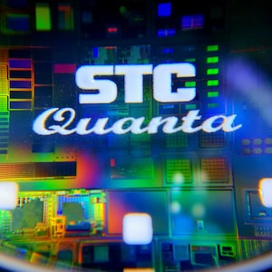 May include: Close-up of a computer chip with the text "STC Quanta" printed on it. The chip is a complex circuit board with many different colored components.