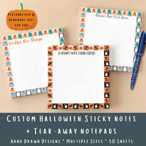 May include: Three square paper notepads with Halloween-themed borders featuring ghosts, pumpkins, and bats. The pads are personalized with the text Emily's Boo Things, Allison's Boo-tiful Ideas, and A SPOOKY NOTE FROM SARAH. A blue pen is included.
