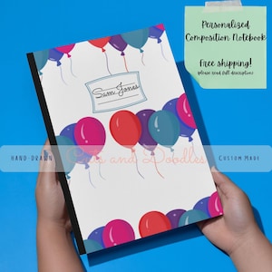 May include: A personalised composition notebook with a colourful balloon design. The notebook has a white cover with a blue frame for a name, and the text "Sam Jones". The notebook is hand-drawn and custom made.