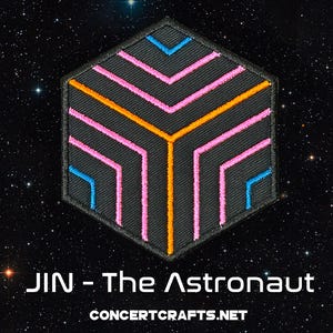 May include: A black hexagonal patch with a geometric design in pink, orange, and blue lines. The text "JIN - The Astronaut" and "CONCERTCRAFTS.NET" are below the patch.