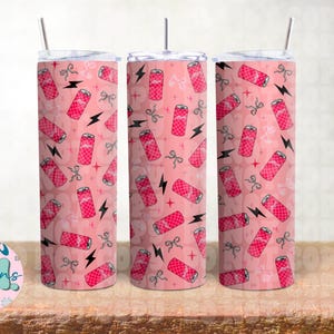 Könnte beinhalten: Drei rosa Becher mit einem sich wiederholenden Muster aus rosa Limonadenbüchsen, Schleifen und Blitzen. Die Becher haben einen silbernen Strohhalm und einen weißen Deckel. Der Hintergrund ist hellrosa.