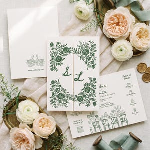 May include: A wedding stationery set featuring cream-colored paper with dark green botanical illustrations and the letters S and L. The set includes a gatefold invitation, an order of events card with icons, and a card with two swans and www.wedding.com.