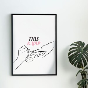 May include: Black framed art print featuring a line drawing of hands during a manicure. The text "THIS & YAP" is in pink and black. A potted plant is in the background.