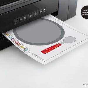 May include: Printable playdough mat featuring a gray frying pan and a red and white polka dot spoon. The mat says "Playdough Mat" and includes the website address "www.thealohahut.com".