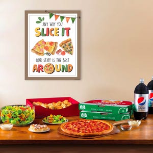Op de afbeelding: Een bord met de tekst "Any way you slice it, our staff is the best around" met een cartoon afbeelding van drie pizzapunten. Een tafel met een pizza, salade, stokbrood en frisdrank.