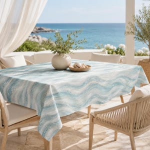 May include: A rectangular tablecloth featuring a repeating pattern of wavy, horizontal lines in shades of light blue, teal, and white. The fabric drapes over a table, displaying a textured appearance with a soft, fluid design across the surface.