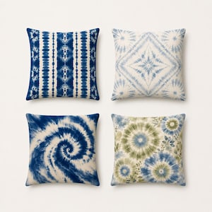 Könnte beinhalten: Ein Set aus vier quadratischen Zierkissen mit verschiedenen Batikmustern. Ein Kissen hat vertikale blaue und weiße Streifen, eines ein blau-weißes Rautenmuster, eines eine große blaue Spirale und eines blaue und grüne florale Kreise.