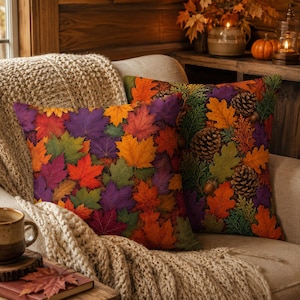 May include: Two square throw pillows featuring a vibrant autumn pattern. One pillow displays a dense arrangement of maple leaves in shades of red, orange, yellow, purple, and green. The other pillow features a mix of oak leaves, pinecones, and acorns.