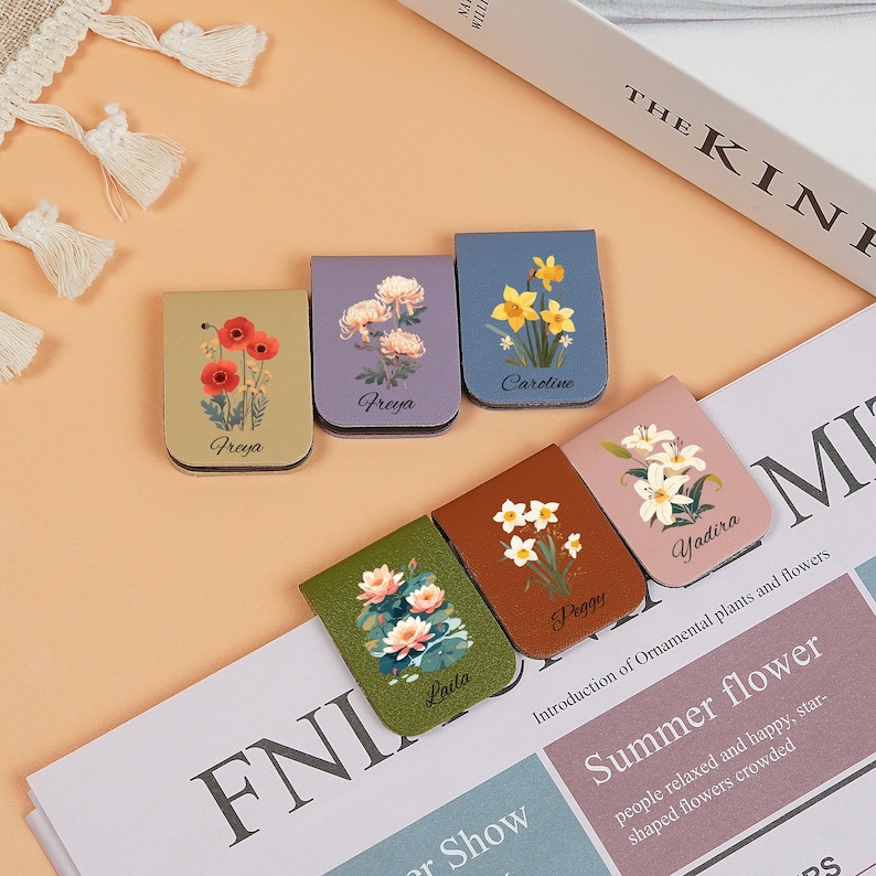 May include: Six colorful magnetic bookmarks with floral designs. Each bookmark features a different flower and the name of the flower is printed on the bookmark. The bookmarks are made of leather and have a magnetic closure.