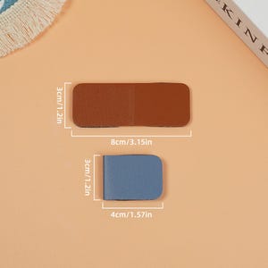 May include: Two leather bookmarks, one brown and one blue, with measurements in inches and centimeters.