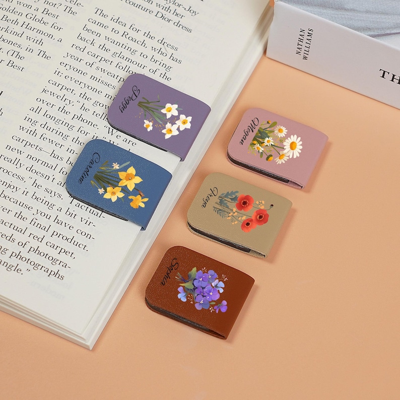May include: Four colorful magnetic bookmarks with floral designs. The bookmarks are labeled with the names "Peggy", "Caroline", "Olivia", and "Sophia".