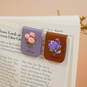 May include: Two personalized leather bookmark magnets with floral designs. The purple magnet features pink roses and the name Kelsie. The brown magnet features purple flowers and the name Sophia.