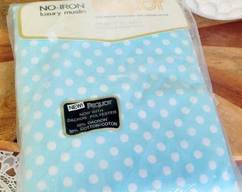 May include: A packaged, light blue double fitted sheet with white polka dots. The packaging reads "NO-IRON luxury muslin" and "NEW! Pequot" with details about the fabric composition.