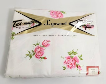 May include: A white fitted sheet with a pink rose pattern. The sheet is packaged in plastic and has a label that reads "Tex-made Lynwood One Fitted Sheet - Select Quality Double Bed Fitted 54 x 75".